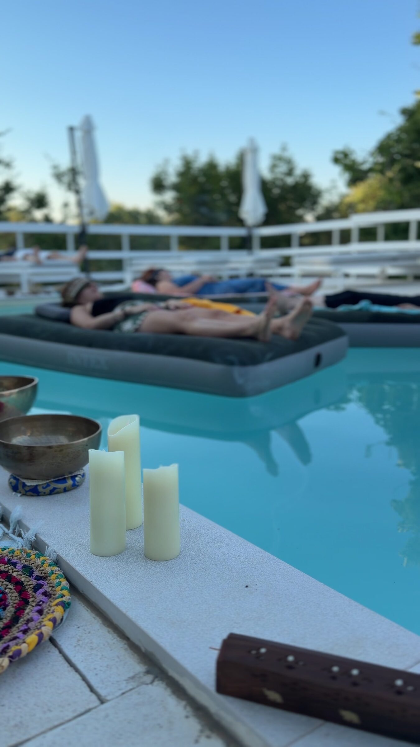 Candele e ciotola tibetana a bordo piscina al tramonto
